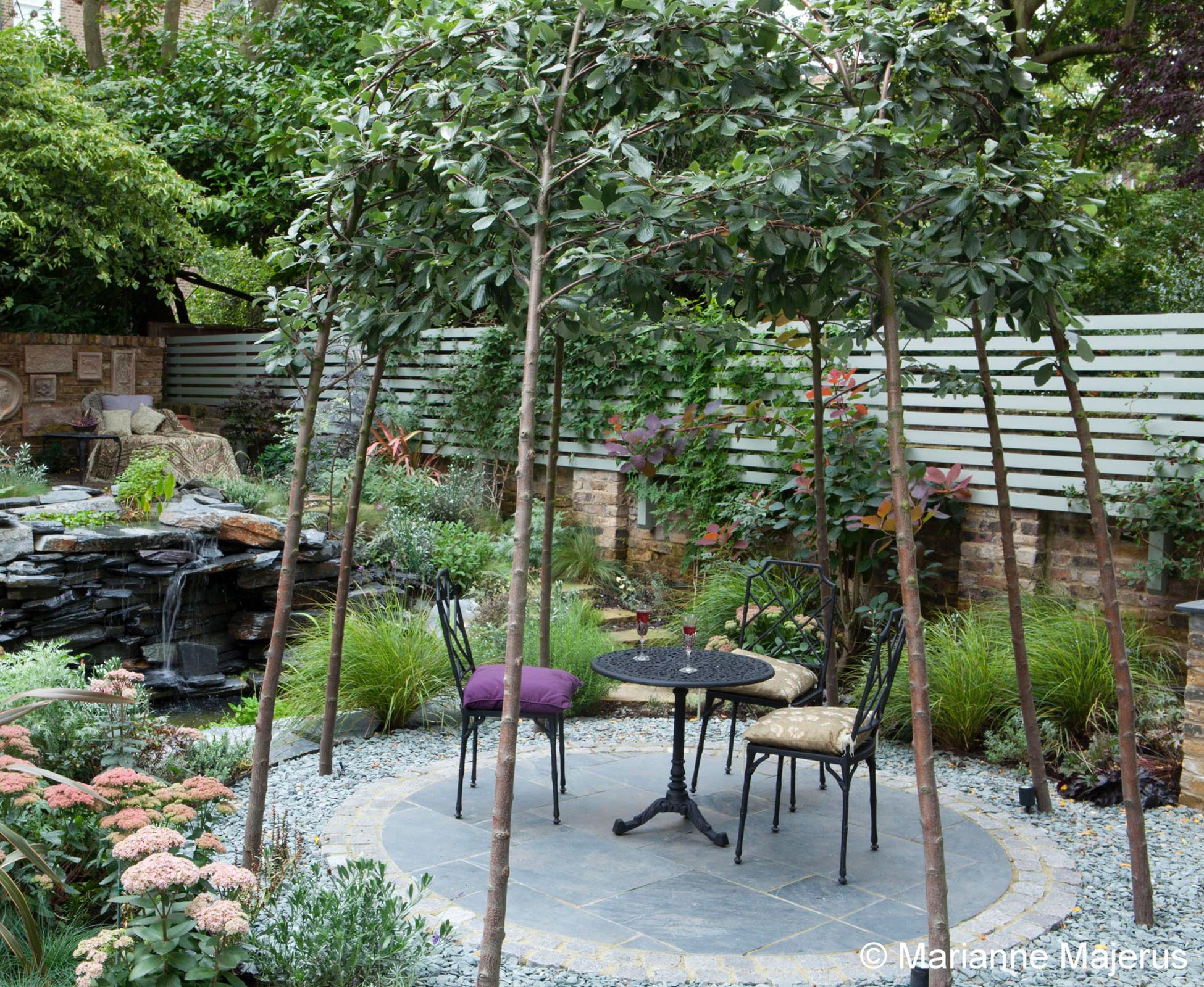 The trees have been trained to create a unusual canopy for the slate patio, that sits in front of the water feature.