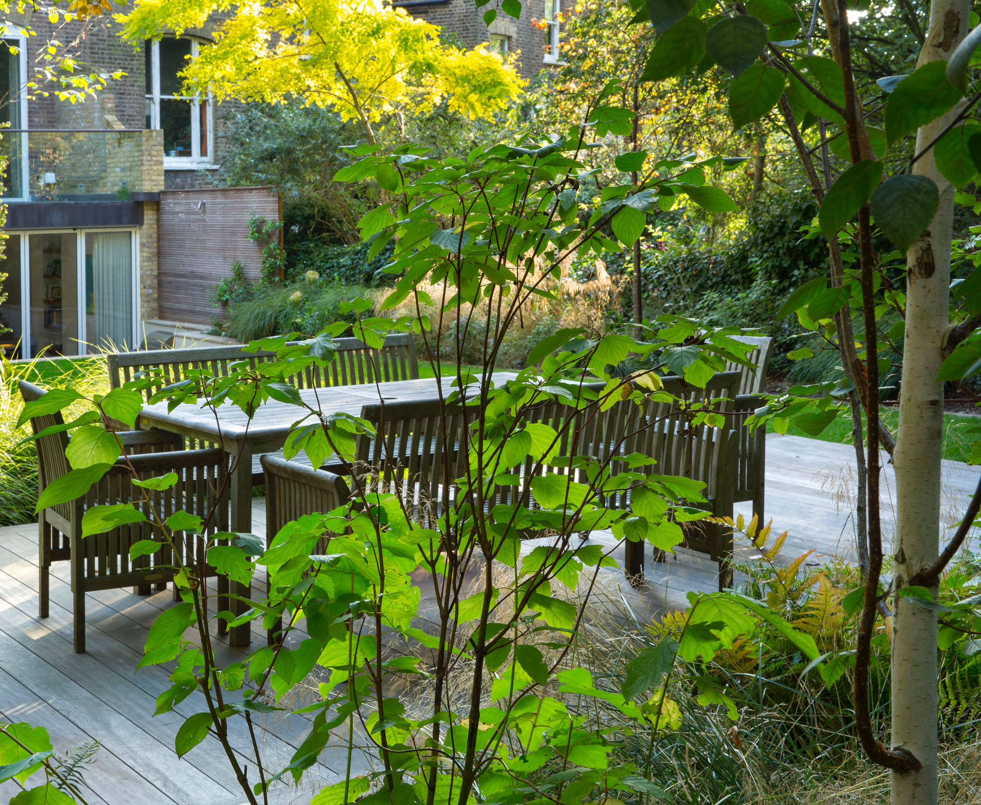 Tucked at the rear of the garden, a raised hardwood timber deck floats above the lawn. Surrounded by lush planting on three sides, it merges with the natural look of the woodland behind, near Hampstead Heath.