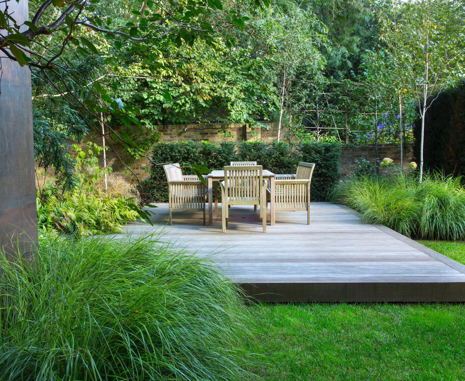 A shadow gap under the hardwood timber deck is a nice detail to lighten the construction. The seating area seems to be floating above the perfect lawn, surrounded by soft herbaceous planting. Some tall birch trees create some intimacy from the neighbours in this Hampstead Heath garden.