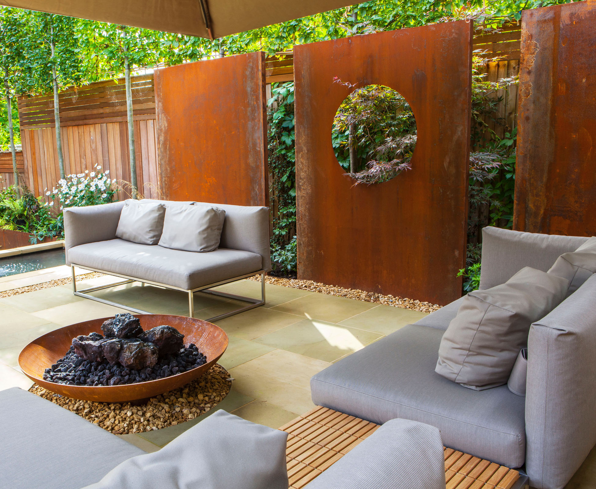 The corten steel firebowl has been installed over a gravel chanel to ensure that the paving doesn’t get any rust stains. The nice detail is continued under the feature panels all around the lounge area.