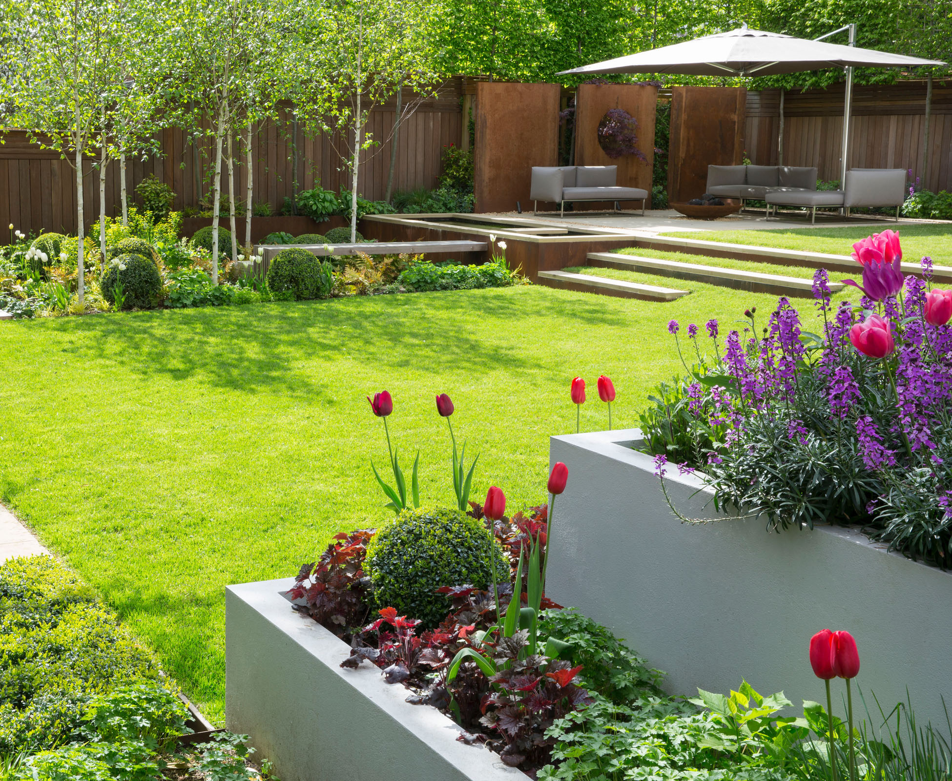 The birch trees cast some light shadows on the lawn when the sun is out. The big parasol over the seating area can be opened when needed and compliment the chosen furniture.